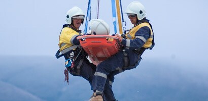 Two rescue workers and injured worker in a litter suspended from rescue device

