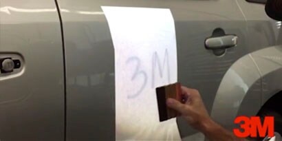 A graphic installer smooths a 3M graphic wrap on a car.
