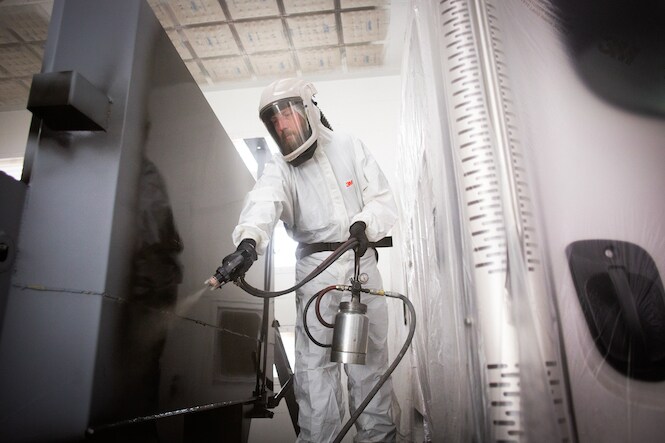 person using an automotive paint spray gun in an industrial setting
