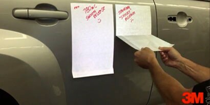 A graphic installer peels the backing of a vehicle wrap from a car.
