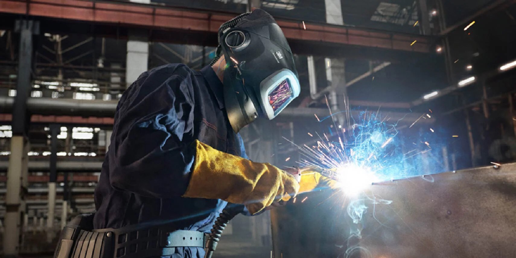 A person wearing a mask and gloves welding
