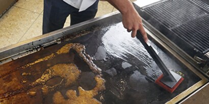 3M Scotch-Brite Quick Clean Heavy Duty Griddle Pad in use on a hot griddle
