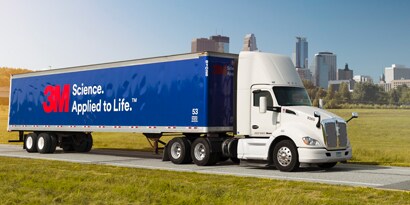 graphic film with 3M logo wrapped on the body of a commercial fleet truck driving down a city road
