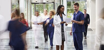 Clinicians standing in a hallway of a busy hospital.
