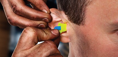 A person putting ear plugs into their ear
