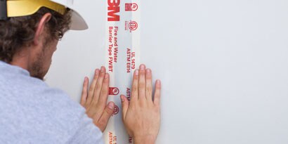 Person applying 3m VHB tape to wall
