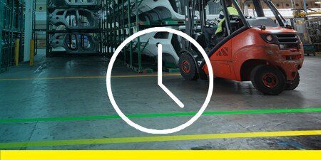 Image of a forklift on a taped off floor placing a vehicle frame on a rack
