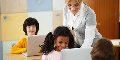 Teacher helping happy students in school