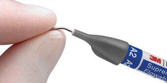 Dentist grabbing 3M flowable composite syringe off dental tray.

