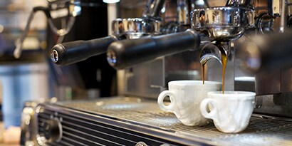 A coffee machine pouring coffee into two cups
