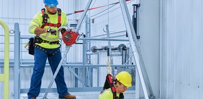 Workers demonstrating portable confined space retrieval tripod
