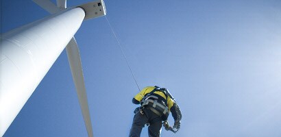 Worker suspended at end of long cable from wind turbine
