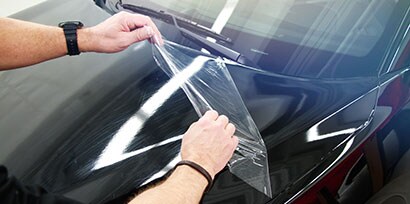 Installer removes the Protective Film Layer of 3M Wrap Film Series 2080 from the hood of a car.
