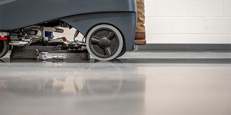 Floor cleaning machine cleaning a concrete floor.
