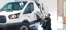 A graphic installer pulling a graphic wrap over a fleet vehicle