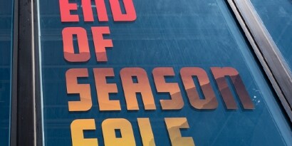 A window has a print film with bold letters that read, “End of season sale.”
