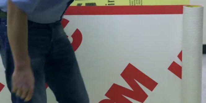 Video still of a construction worker walking past a wall covered with a 3M Air Barrier Membrane
