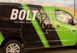 A van with a green-and-white striped fleet wrap displays the word “BOLT” and a lightning bolt.